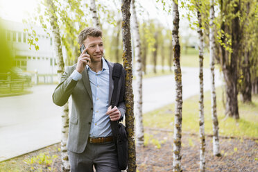 Businessman on cell phone in a park - DIGF06906