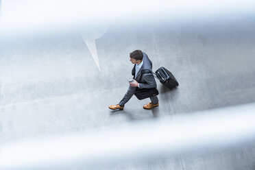 Top view of businessman walking with baggage and takeaway coffee - DIGF06911