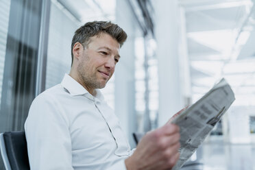 Geschäftsmann sitzt im Wartebereich und liest Zeitung - DIGF06914