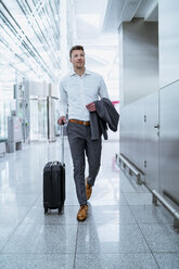 Businessman walking with baggage at the airport - DIGF06920