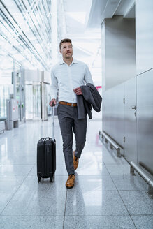 Businessman walking with baggage at the airport - DIGF06920