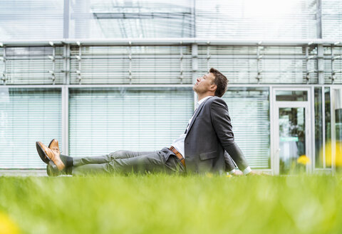 Relaxed businessman having a break sitting in grass - DIGF06921