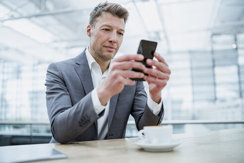 Geschäftsmann benutzt Mobiltelefon in einem Café - DIGF06926