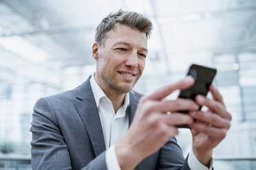 Porträt eines lächelnden Geschäftsmannes, der ein Mobiltelefon benutzt - DIGF06927