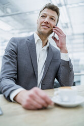 Businessman on cell phone in a cafe - DIGF06928