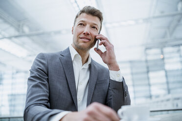 Businessman on cell phone in a cafe - DIGF06930