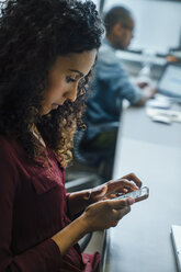 Businesswoman using cell phone in office - BLEF01990