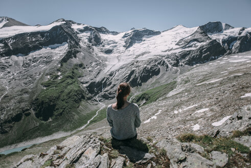 Kaukasische Frau sitzt auf einem Felsen und bewundert die schöne Aussicht auf einen Berg - BLEF02030