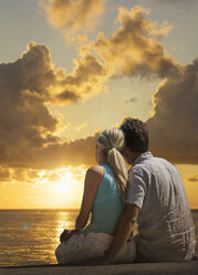 Caucasian couple admiring scenic view of sunset at ocean - BLEF02034