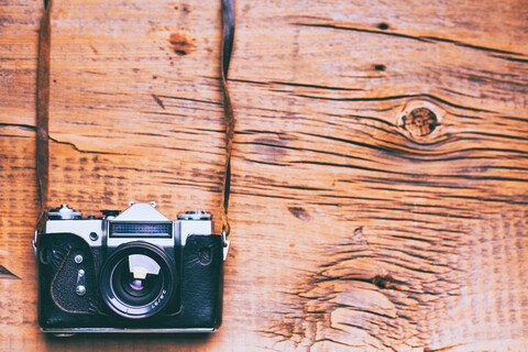 Kamera und Gurt auf Holztisch, lizenzfreies Stockfoto