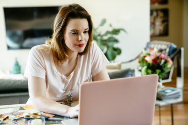 Frau sitzt am Tisch und benutzt einen Laptop - BLEF02064