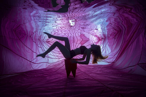 Young woman posing underwater in front of backlit and parachute - YRF00212