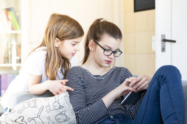Zwei Schwestern schauen sich zu Hause ein digitales Tablet an - LVF08010