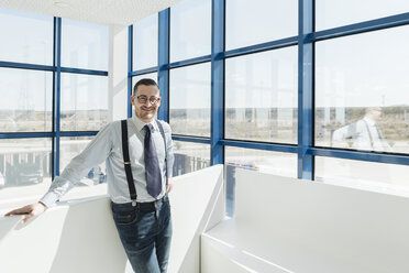 Porträt eines selbstbewussten Geschäftsmannes am Fenster in einem modernen Büro - AHSF00205