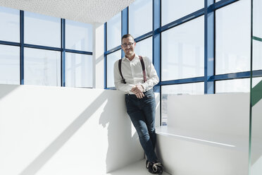 Porträt eines selbstbewussten Geschäftsmannes am Fenster in einem modernen Büro - AHSF00210