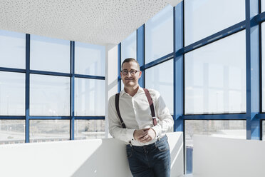 Porträt eines selbstbewussten Geschäftsmannes am Fenster in einem modernen Büro - AHSF00211