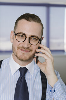 Porträt eines zuversichtlichen Geschäftsmannes mit Mobiltelefon - AHSF00227