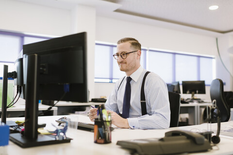 Geschäftsmann mit Computer am Schreibtisch im Büro, lizenzfreies Stockfoto