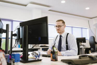 Geschäftsmann mit Computer am Schreibtisch im Büro - AHSF00235