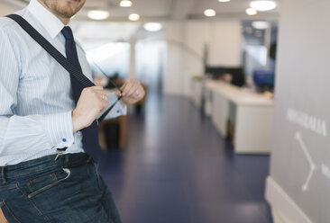 Nahaufnahme eines Geschäftsmannes, der mit Hosenträgern im Büro posiert - AHSF00239