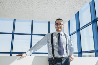 Porträt eines selbstbewussten Geschäftsmannes am Fenster in einem modernen Büro - AHSF00241