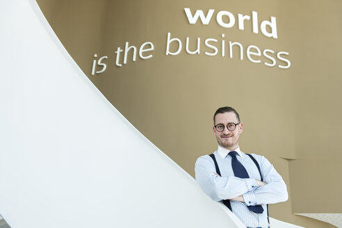 Porträt eines selbstbewussten Geschäftsmannes auf einer Treppe in einem modernen Büro - AHSF00250