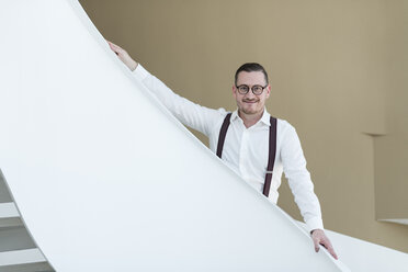 Portrait of confident businessman on stairs in modern office - AHSF00256