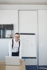 Porträt eines selbstbewussten Geschäftsmannes mit Laptop im Konferenzraum eines Büros - AHSF00269