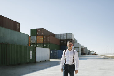 Manager in front of cargo containers on industrial site - AHSF00271