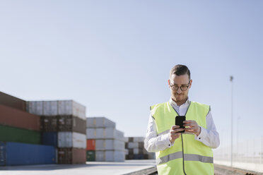 Mann auf Bahngleisen vor Frachtcontainern mit Mobiltelefon - AHSF00290