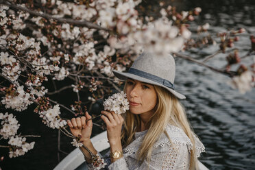 Japan, Tokio, Chidorigafuchi Park, woman in rowing boat smelling at cherry tree blossom - LHPF00709