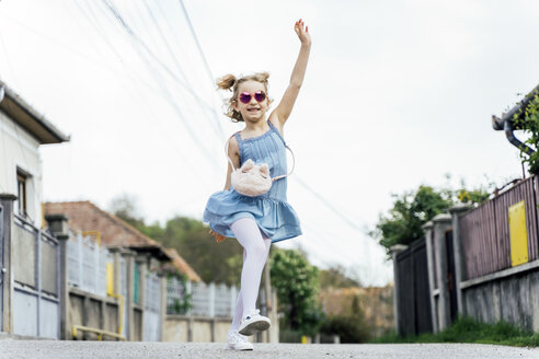 Happy little girl dancing on the street - OCMF00448