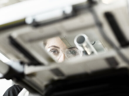 Frau arbeitet an einer Maschine und schaut in die Kamera - CVF01170