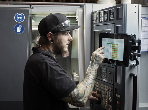 Mann mit Tattoos bei der Arbeit an einer Maschine, lizenzfreies Stockfoto