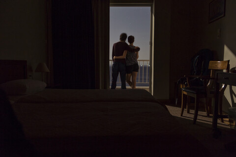 Griechenland, Paar auf Balkon bei Nacht mit Blick auf das Meer, lizenzfreies Stockfoto