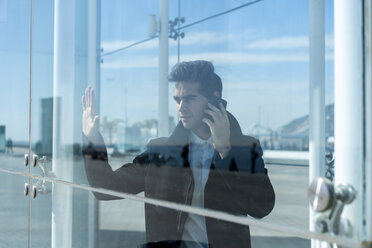 Businessman on the phone in the city behind glass pane - AFVF02829