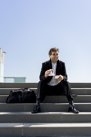 Glücklicher Geschäftsmann auf der Treppe sitzend in der Mittagspause, lizenzfreies Stockfoto