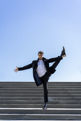 Businessman standing on on leg on stairs - AFVF02846