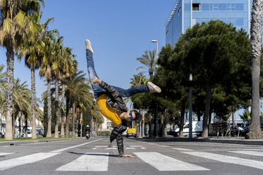 Spanien, Barcelona, Mann in der Stadt macht einen Handstand auf der Straße - AFVF02881