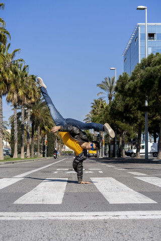 Spanien, Barcelona, Mann in der Stadt macht einen Handstand auf der Straße, lizenzfreies Stockfoto