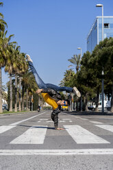Spanien, Barcelona, Mann in der Stadt macht einen Handstand auf der Straße - AFVF02882