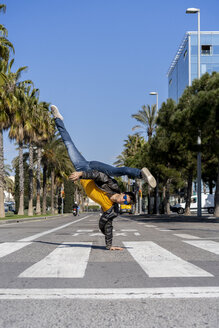 Spanien, Barcelona, Mann in der Stadt macht einen Handstand auf der Straße - AFVF02882