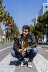 Spain, Barcelona, man crouching on zebra crossing - AFVF02887