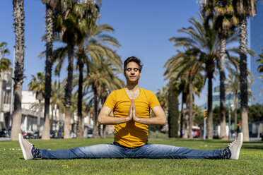 Spain, Barcelona, man practicing yoga on lawn in the city - AFVF02898