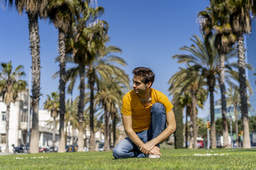 Spain, Barcelona, man on lawn in the city looking around - AFVF02900