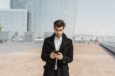 Portrait of businessman holding cell phone in the city - AFVF02907