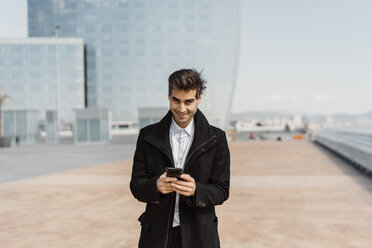 Portrait of smiling businessman holding cell phone in the city - AFVF02908