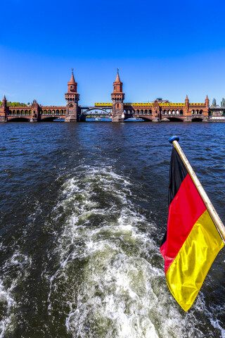 Deutschland, Berlin, Oberbaumbrücke und deutsche Flagge auf Ausflugsschiff auf der Spree, lizenzfreies Stockfoto