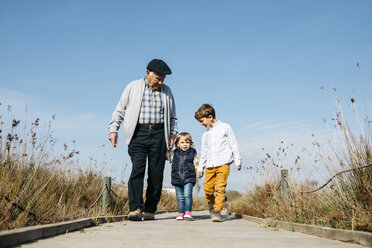 Großvater schlendert mit seinen Enkelkindern Hand in Hand über die Promenade - JRFF03177