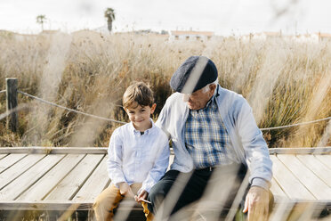 Grandfather sitting with his grandson on boardwalk relaxing - JRFF03181